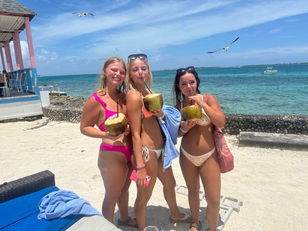girls on the beach Girls on the beach in swimsuits drinking from coconuts.