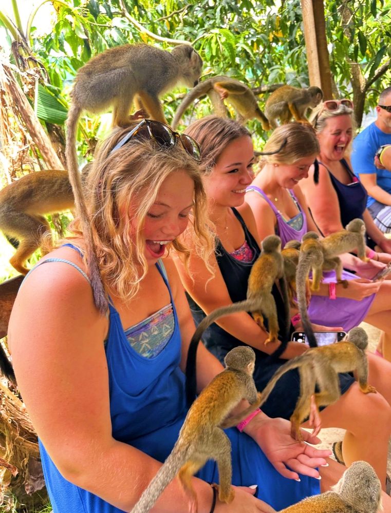 Party Photo Girls sitting in a row with monkeys climbing all over them.